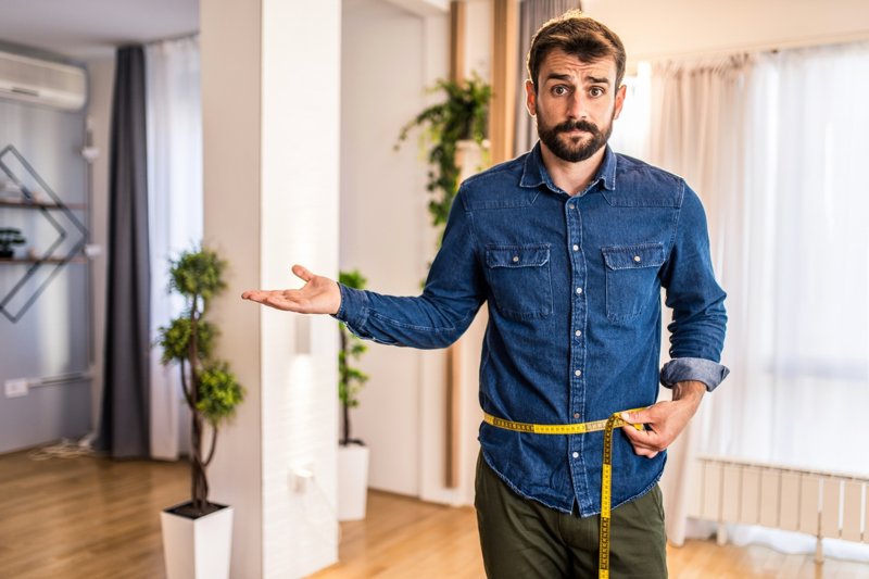 άντρας μετράει με μεζούρα την κοιλιά του